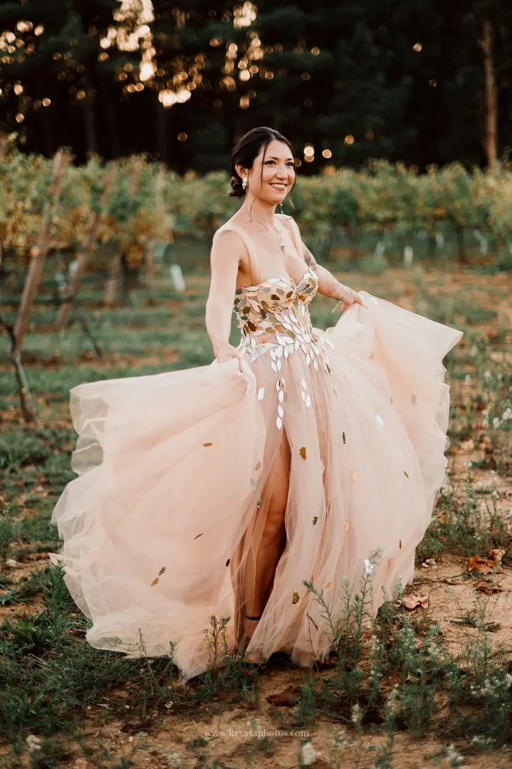 Bride in whimsical blush pink wedding dress posing for stunning portraits in lush Portugal vineyards