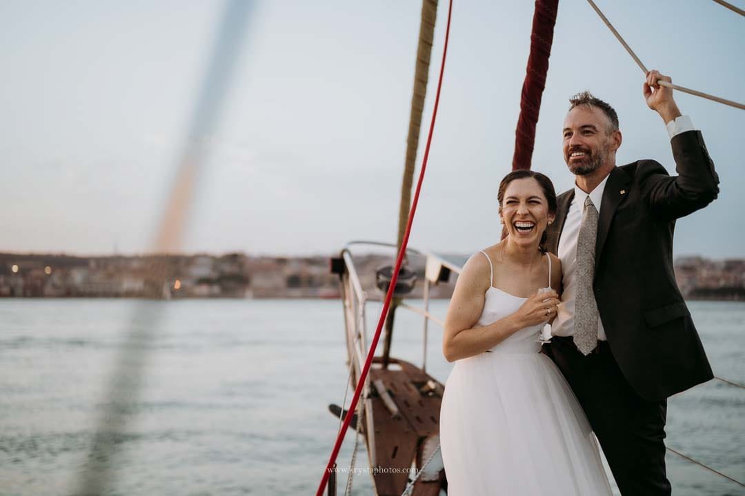 Bride and groom enjoying a cheese and cold cuts board with bubbly on a sailboat during their sunset cruise in Lisbon.