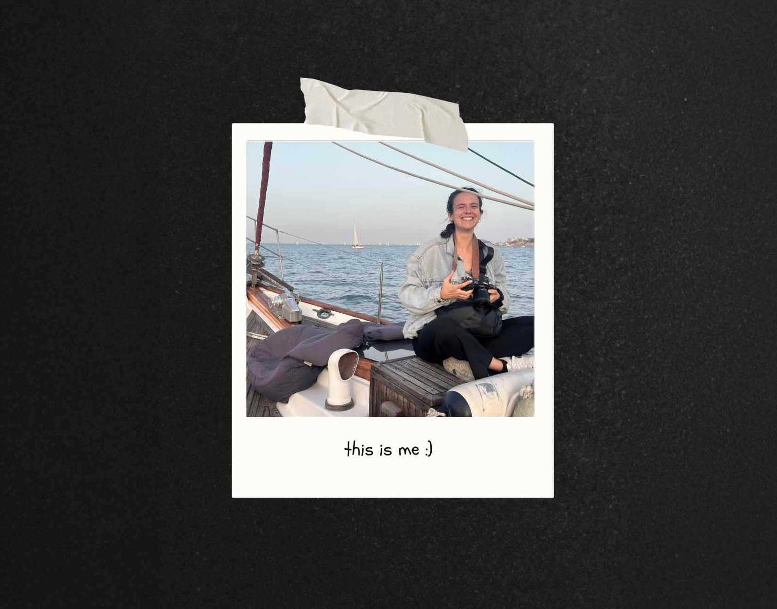 Wedding photographer smiling and holding a camera on a sailboat during a sunset cruise in Lisbon.