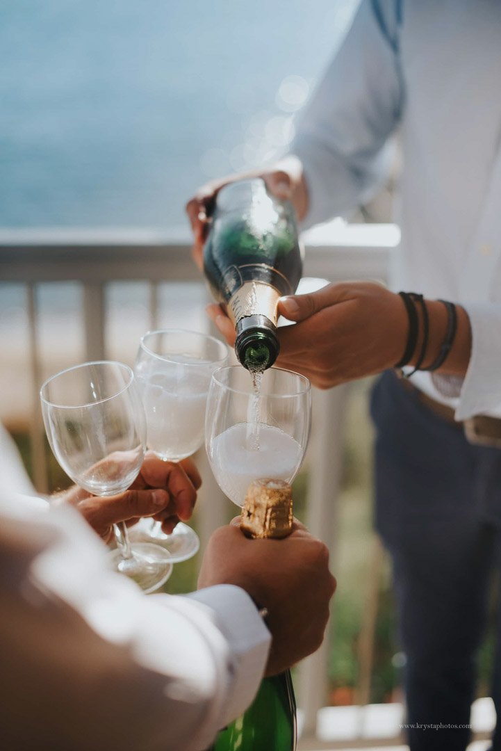 Groomsmen opening champagne during wedding prep with sea view on Greek island
